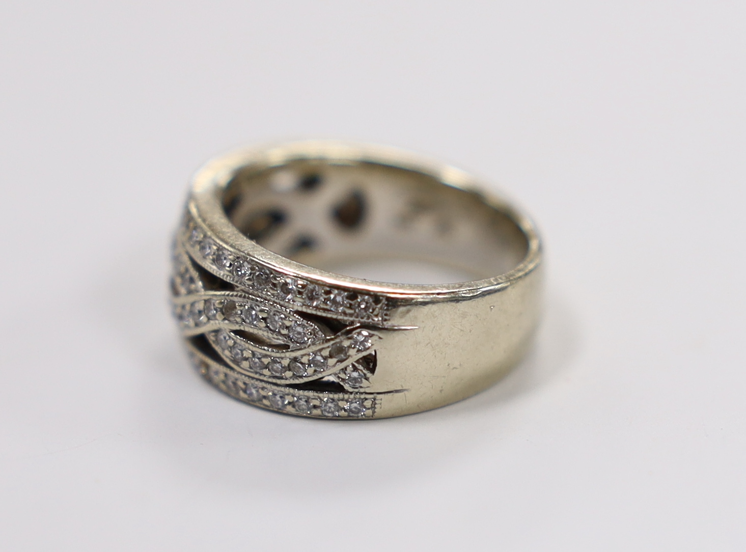 A modern 14ct white gold and diamond chip set spiral cluster ring with diamond set borders, size L, gross weight 7.2 grams.